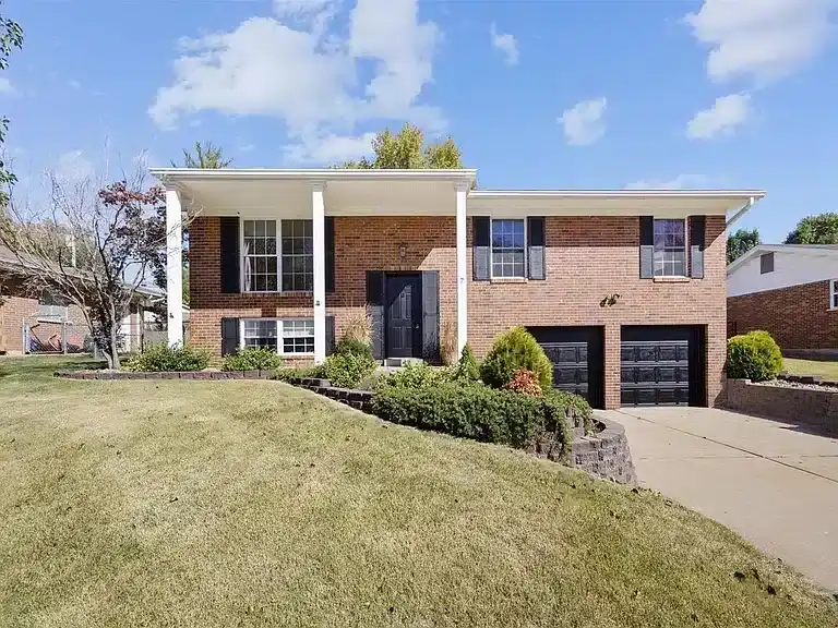 The front of a brick home with white pillars in Fenton, Missouri